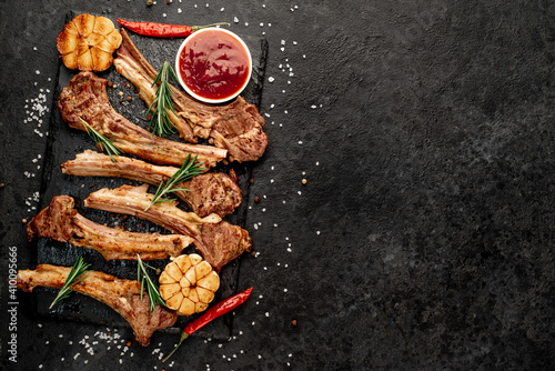 Grilled lamb ribs with spices and garlic on a stone background with copy space for your text