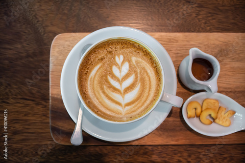 Hot coffee cup of latte art, coffee on the Saucer, and Snacks on a wooden table in the morning.