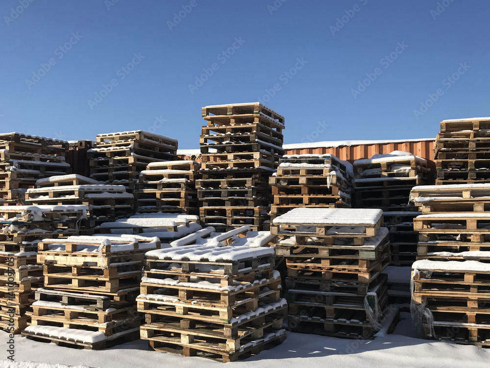 Old pallets assembled into a tower. Snow lies on pallets.