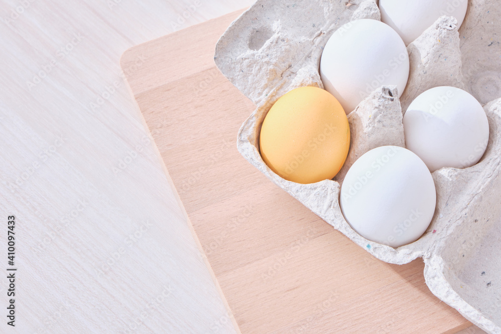 Minimal concept Easter. eggs in a cardboard box and a wooden cutting board on the table Minimal concept Easter. eggs in a cardboard box and a wooden cutting board on the table