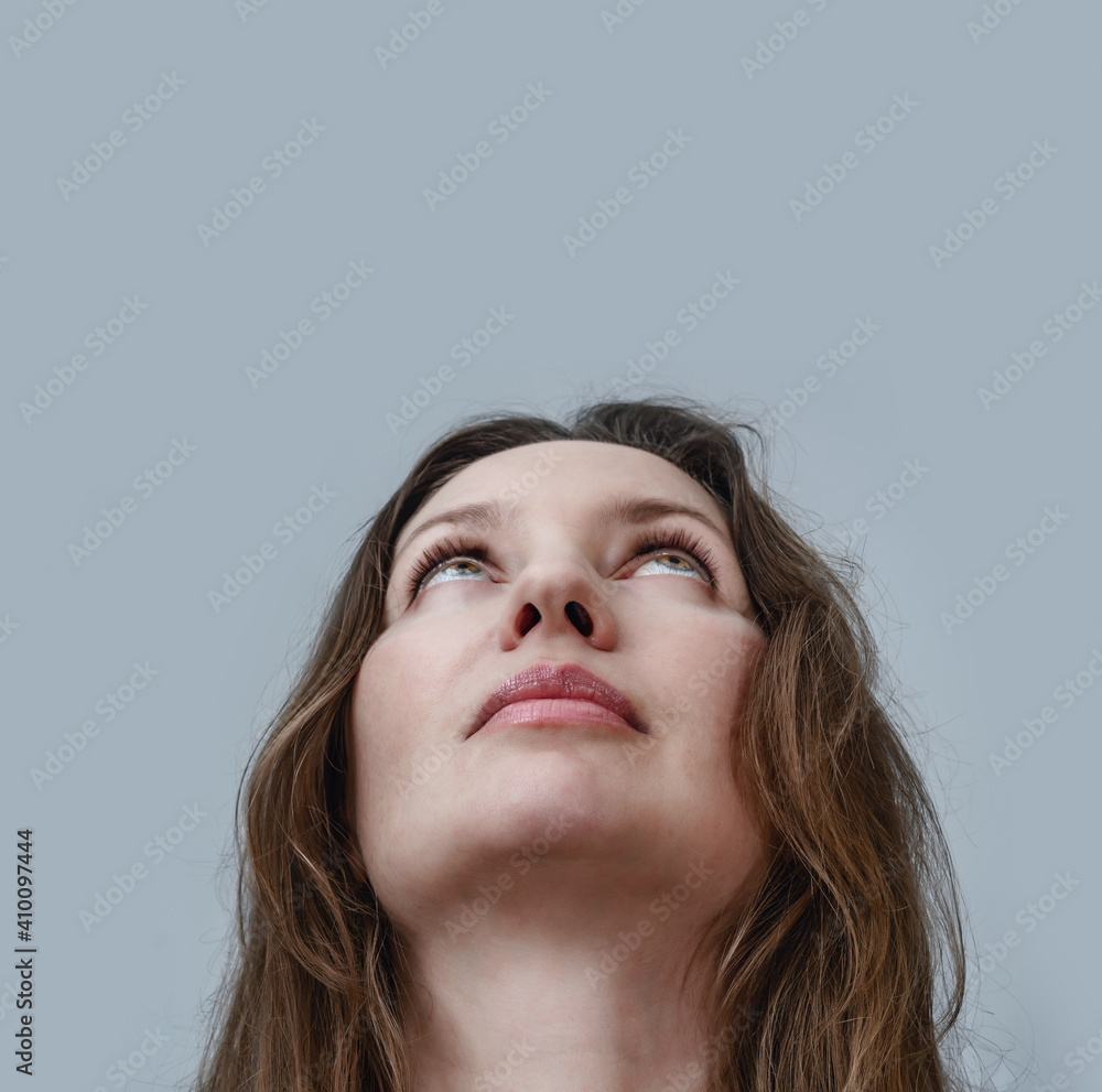 Portrait of a beautiful woman shot from below looking up on a gray background Portrait of a beautiful woman shot from below looking up on a gray background