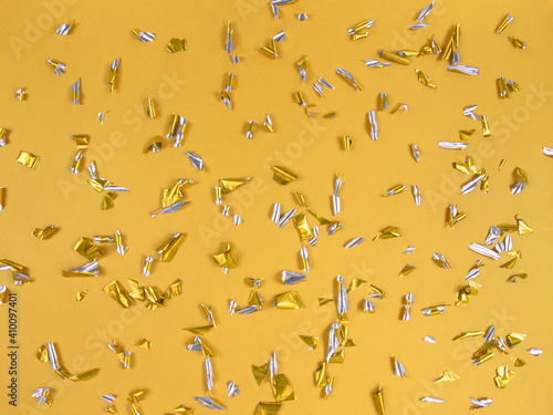 Confetti foil pieces on yellow background. Abstract festive backdrop. © Анна О
