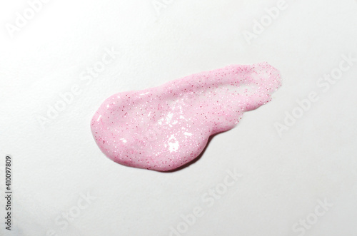 Pink cosmetics smear with glitter on the white background
