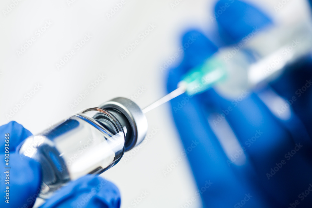Hand in blue gloves holding syringe with needle inserted into ampoule with antiviral liquid - obrazy, fototapety, plakaty 