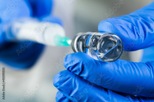 Photographie COVID-19 UK vaccine clinical trial concept,hands in blue gloves holding bottle v