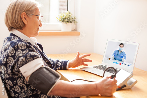 Fotografija Elderly senior retired woman using sphygmomanometer blood pressure monitor to me