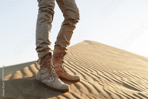 A tourist stands in the desert in beige pants and boots