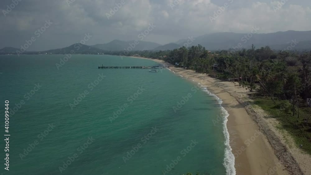 Drone scene- view of clean and green tropical beach - passing beach and over trees and the thai flag - koh samui island in Thailand Drone scene- view of clean and green tropical beach - passing beach and over trees and the thai flag - koh samui island in Thailand