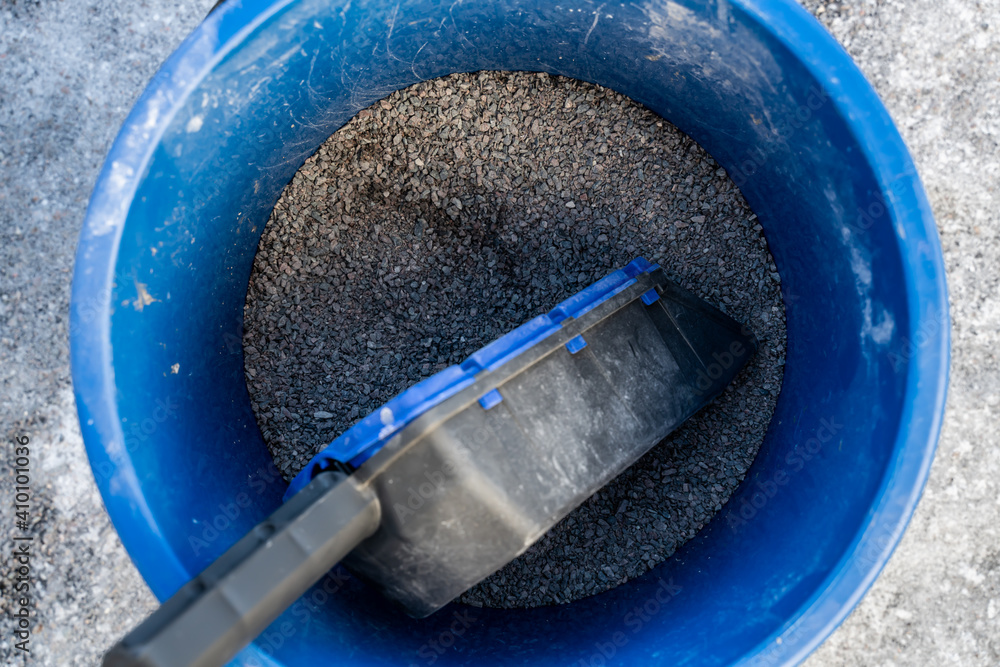 Blue bucket with gravel for icy roads and sidewalks. Shallow field of view. Blue bucket with gravel for icy roads and sidewalks. Shallow field of view.