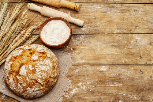 Fresh baked bread with wheat ears, bowl of flour and rolling pins