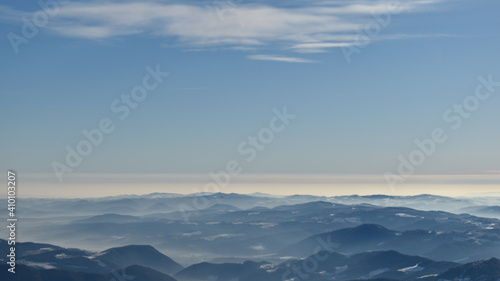 Landscape with hills up to the horizon, blue sky and snow in winter