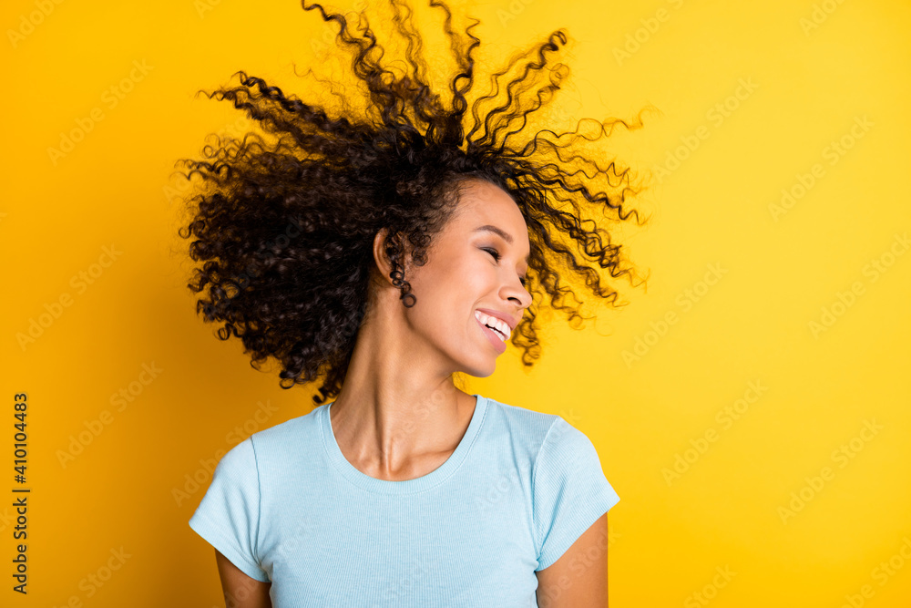Photo of pretty adorable dark skin wavy lady wear blue t-shirt smiling wind blow hair isolated yellow color background Photo of pretty adorable dark skin wavy lady wear blue t-shirt smiling wind blow hair isolated yellow color background