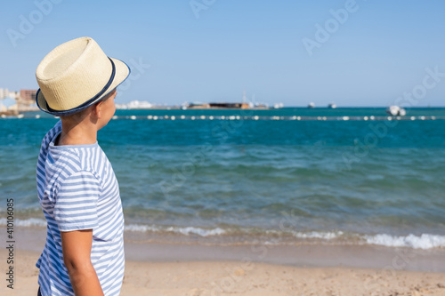 Stylish Boy With Hat on Summer Beach Looking Into Distance to Sea Summer Vacation Concept