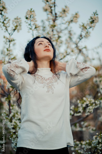 Obraz na płótnie Nice looking girl holding from her neck and looking at the sky in spring, during cherry blossom w salonie
