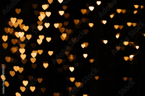 Gold background bokeh lights heart, valentine backgrounds, blurred sparkle for night backdrop. Defocused Theme of love banner. Loving, positive emotions. The concept of celebration and love..