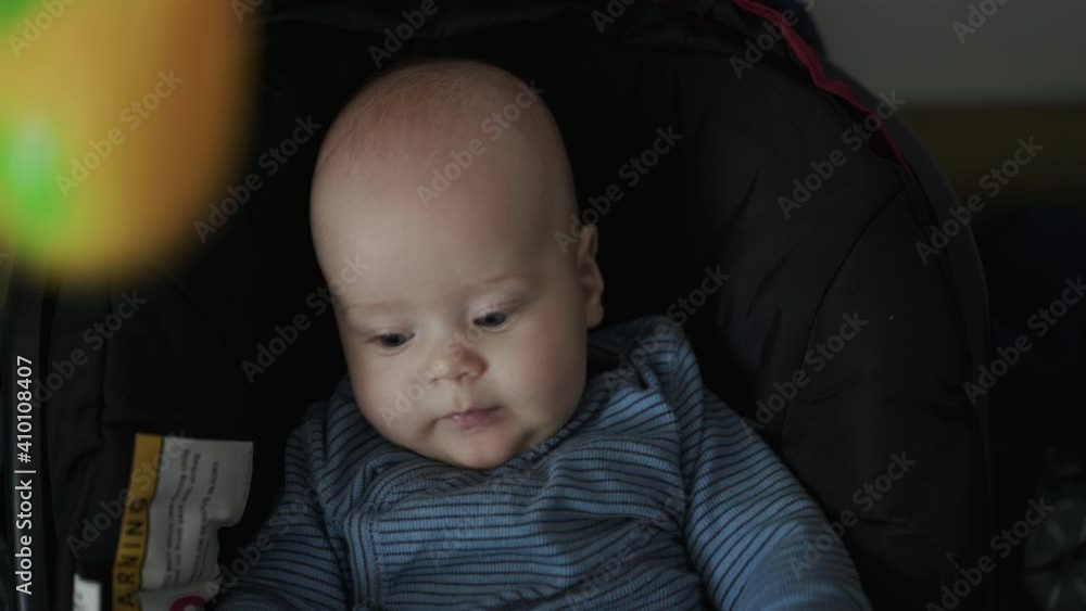 Cute toddler watching when parent's hand entertains him with a toy Cute toddler watching when parent's hand entertains him with a toy