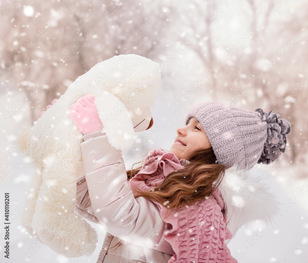 Little girl with a teddy bear stands on the street under the flying snow. winter day Little girl with a teddy bear stands on the street under the flying snow. winter day