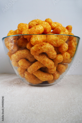 peanut flips . lots of corn sticks in peanut butter frosting in a glass round bowl on a gray light background side view