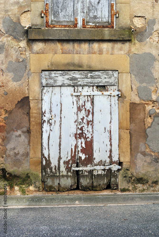Old Weathered Wooden Door on Old Stone Building beside Street 
