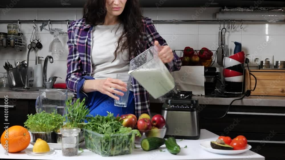 woman drinking fresh handmade green detox smoothie in kitchen. Healthy eating, vegetarian food, cooking, diet concept woman drinking fresh handmade green detox smoothie in kitchen. Healthy eating, vegetarian food, cooking, diet concept