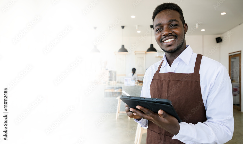 Handsome African waitress holding tablet and show bright smile for welcome customer come in coffee cafe or Restaurant. Small businesses and New normal. Soft focus Handsome African waitress holding tablet and show bright smile for welcome customer come in coffee cafe or Restaurant. Small businesses and New normal. Soft focus