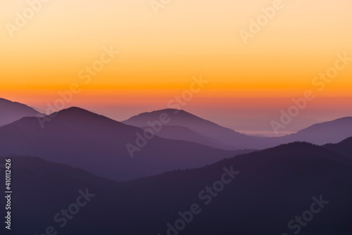 Silhouette of mountain ranges in the haze at dawn.