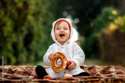 Little girl eating a bagel in the park sitting on a blanket