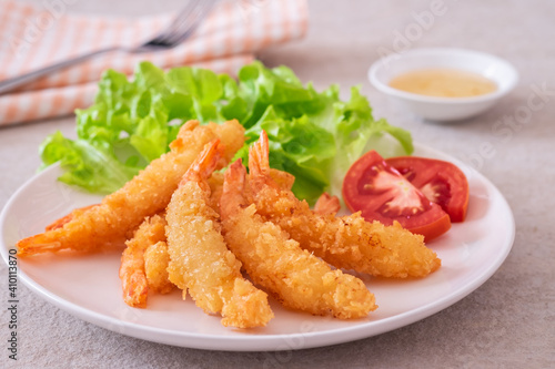 Fried breaded shrimp with vegetable on plate and plum sauce..