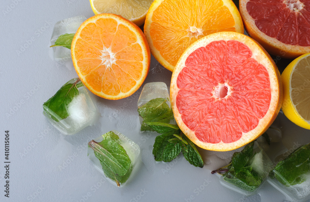 Fresh citrus and mint cut in half on a gray background. Juicy grapefruits, tangerines, lemons, oranges. Preparation of cold juices and drinks.Citrus juice ingredients, food background Fresh citrus and mint cut in half on a gray background. Juicy grapefruits, tangerines, lemons, oranges. Preparation of cold juices and drinks.Citrus juice ingredients, food background