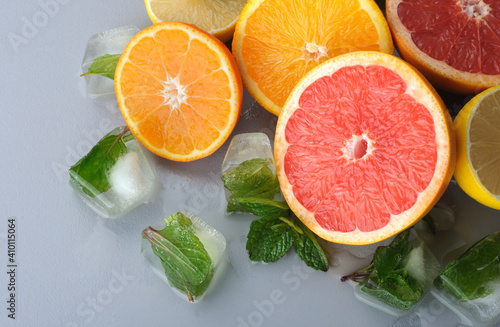 Fresh citrus and mint cut in half on a gray background. Juicy grapefruits, tangerines, lemons, oranges. Preparation of cold juices and drinks.Citrus juice ingredients, food background