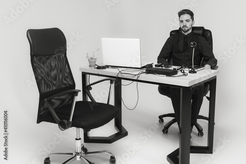young handsome man with a beard in a bright room sitting at a table, working, on the table are sensors on his fingers and body lie detector,  for polygraph. black and white photo © Jurii