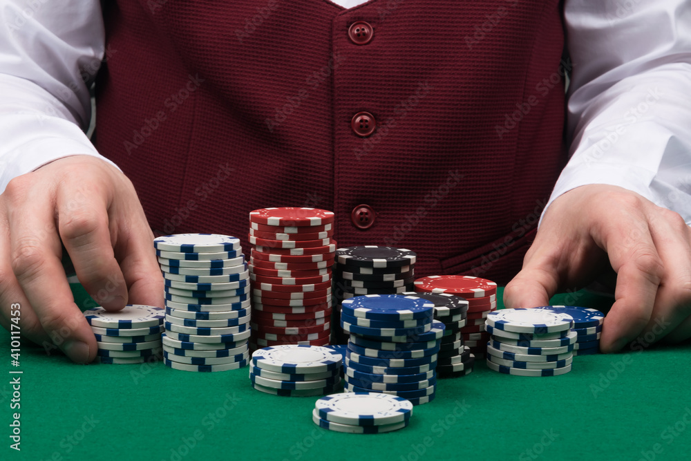 the croupier at the green poker table is sorting out the poker chips the croupier at the green poker table is sorting out the poker chips