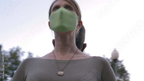 Man and a woman stand with their backs to each other wearing textile protective masks. photo