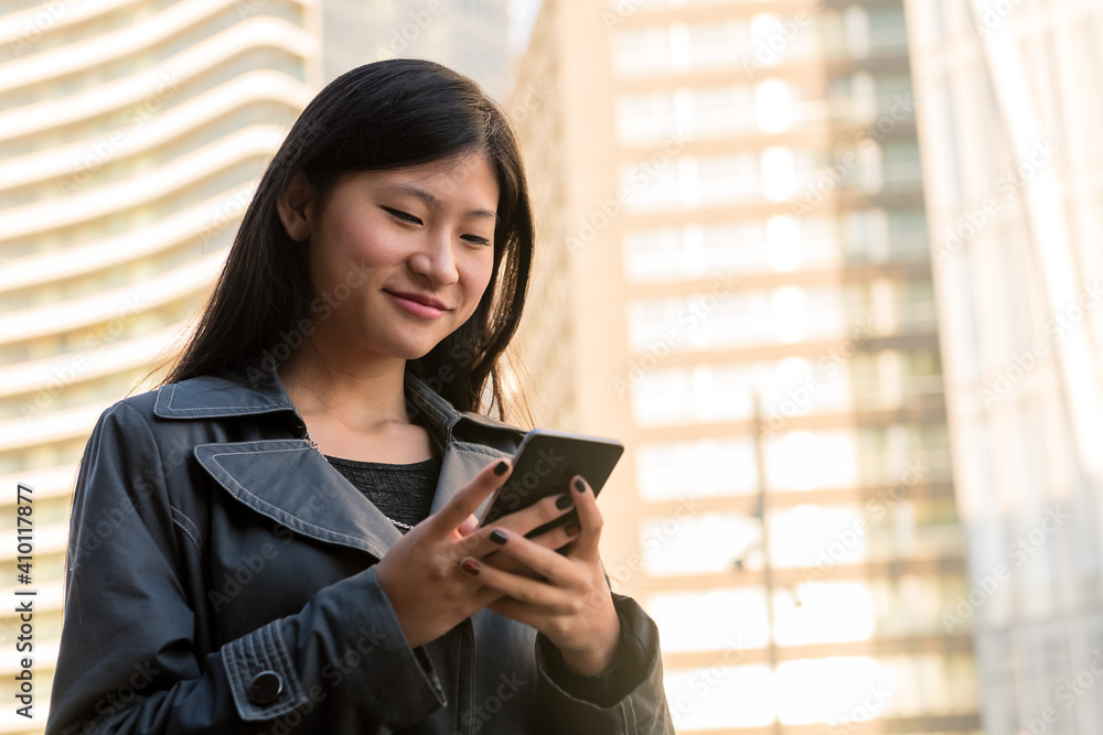 smiling asian woman consulting her mobile phone smiling asian woman consulting her mobile phone