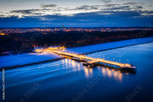 Illuminated pier in Brzezno on the winter beach at dusk, Gdansk. Poland.