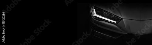 Detail on one of the LED headlights super car on black background, free space on left side for text