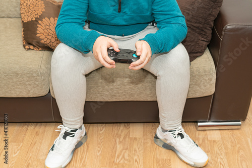Excited teenage gamer is playing game console, controller or console joystick looking at the TV screen in hand sitting on the couch at home...