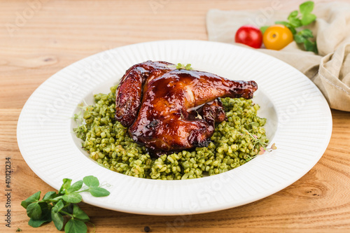 Chicken in barbecue sauce with couscous on a light wooden background.