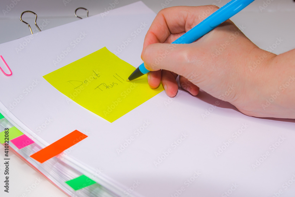 Close-up of a hand writing on a yellow paper. Horizontal photography. Information overload concept Close-up of a hand writing on a yellow paper. Horizontal photography. Information overload concept