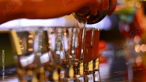 barman pouring shot cocktails into glass in a dark bar
