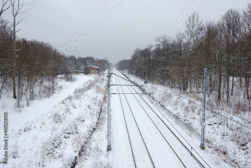 Dwutorowy szlak kolejowy zimą z przejeżdżającą lokomotywą elektryczną. © boguslavus