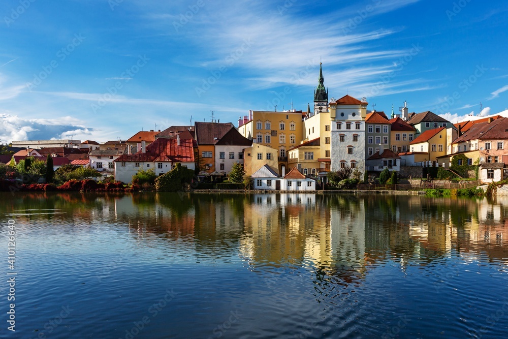 Jindrichuv Hradec, Czech Republic - September 26 2019: View of the cityscape with historical buildings over the small Vajgar lake. Reflection in water. Bright sunny day with blue sky and clouds.