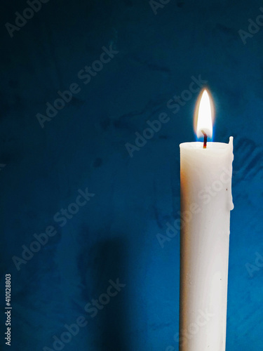 Light candle, on dark aquamarine background. Candle light in black background.
