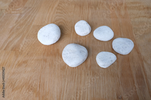 six flat white stones lie on a natural wooden background, background with space, concept of spa procedures, massage, fortune telling on ancient runes