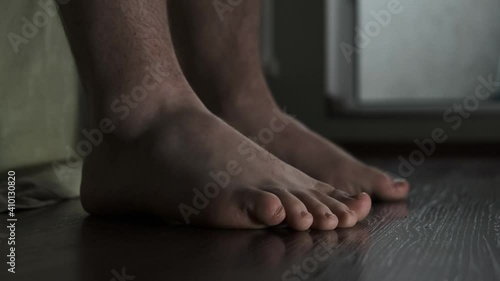 man sitting at home next to bed and bangs bare feet on floor. nervous man at home