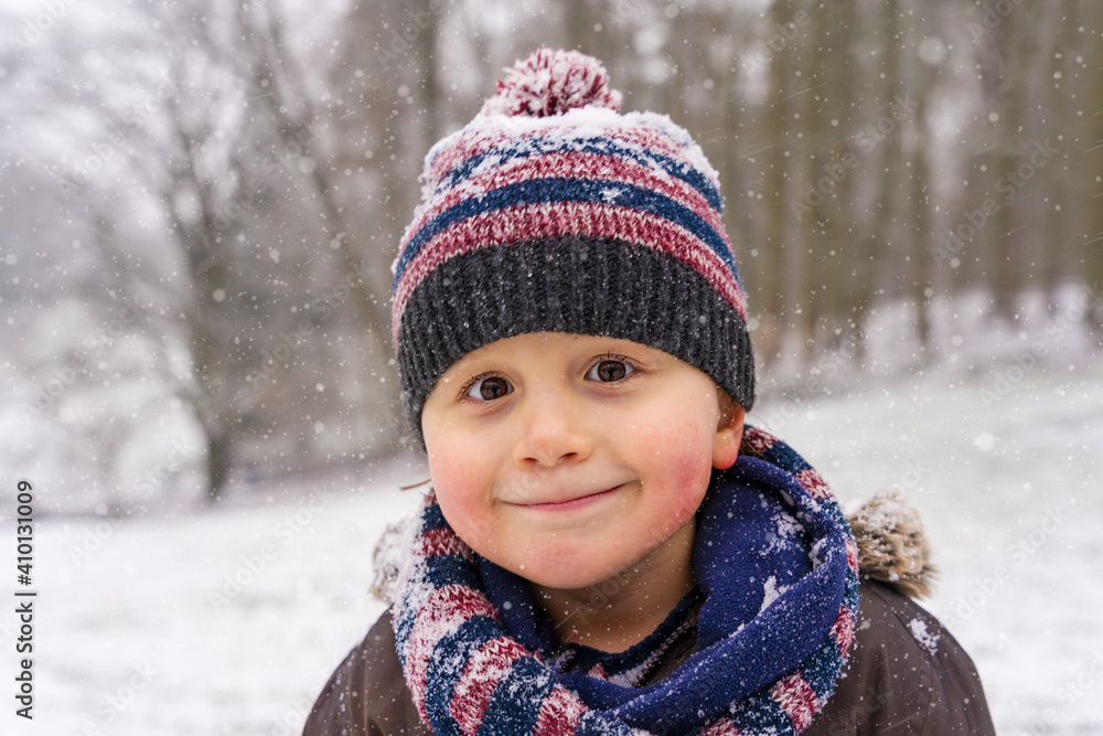 Portrait of little boy wearing warm hat and scarf snood in the park in winter. Happy toddler enjoying snow and frosty weather. Portrait of little boy wearing warm hat and scarf snood in the park in winter. Happy toddler enjoying snow and frosty weather.