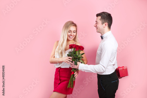 Valentines day. Handsome elegant boy is proposing to his beautiful girlfriend with her roses and smiling.