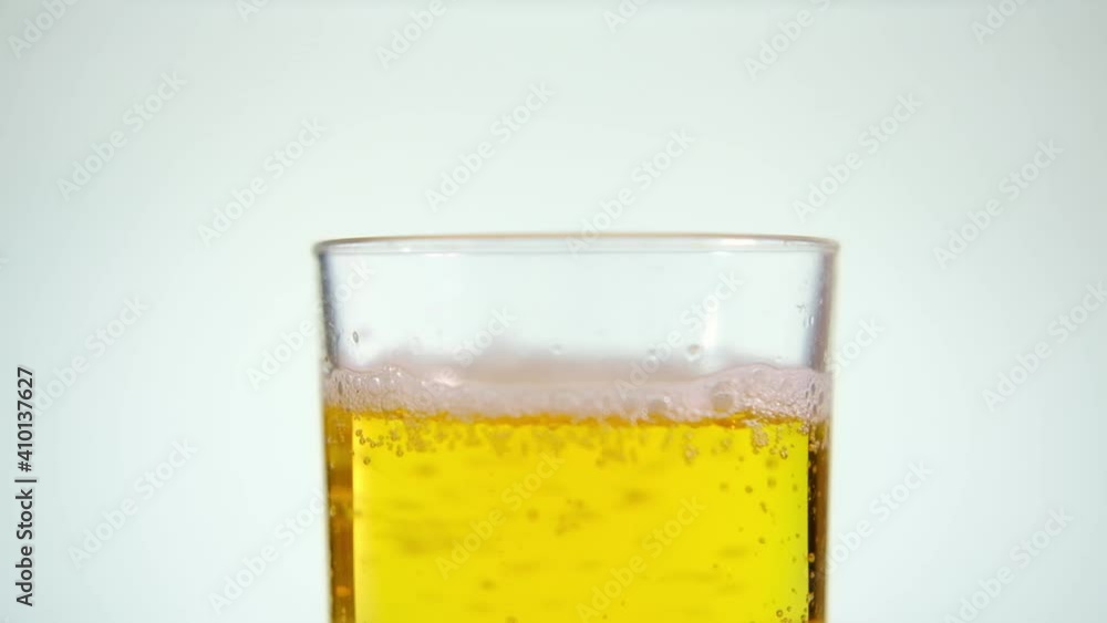 Beer is poured into a glass on a white background. Beer is poured into a glass on a white background.