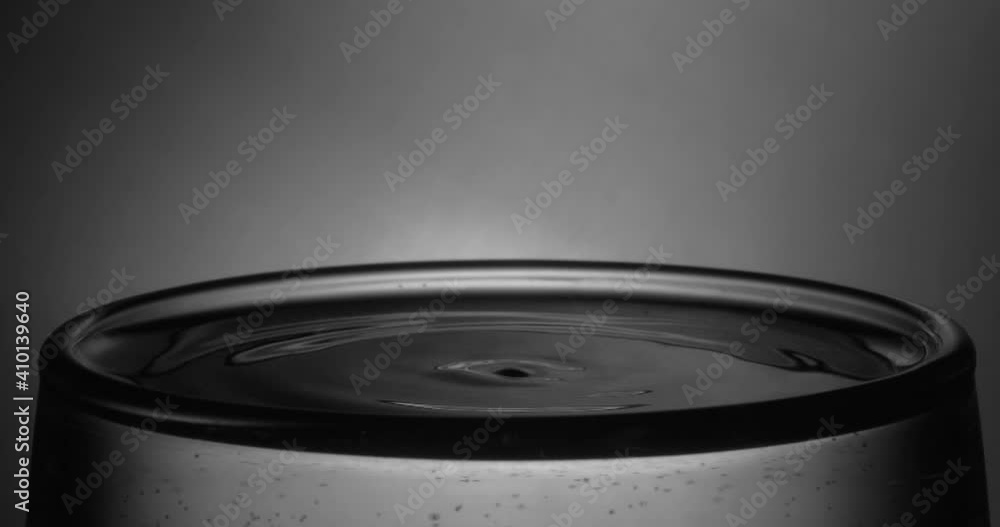 A drop of water drips into a full glass of water. Super slow motion. A drop of water drips into a full glass of water. Super slow motion.