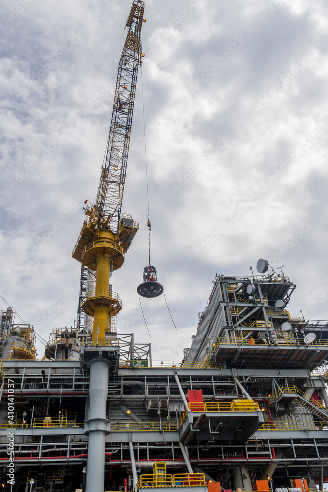 Offshore personnel being lifted with crane on a personal-transfer-basket from an oil production platform to a crew boat for crew change Offshore personnel being lifted with crane on a personal-transfer-basket from an oil production platform to a crew boat for crew change